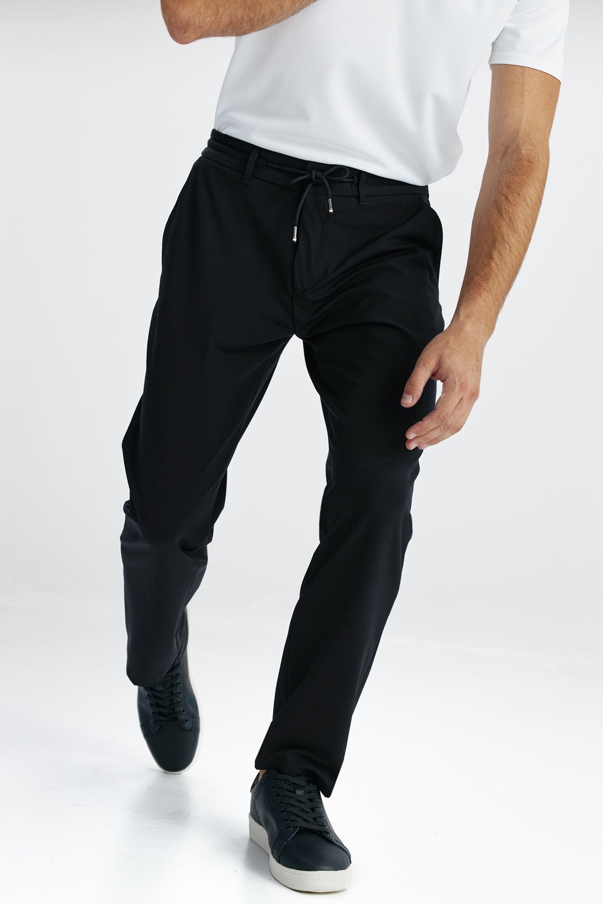 Joggers smart fit color negro con diseño formal, cintura elástica y ajustable, tejido transpirable y resistente, ideales para viajar con estilo y comodidad. Foto detalles.